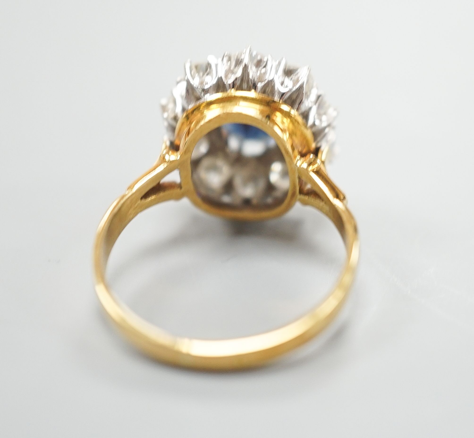 A modern 18ct gold, sapphire and diamond set oval cluster ring, size P/Q, gross weight 6.2 grams.